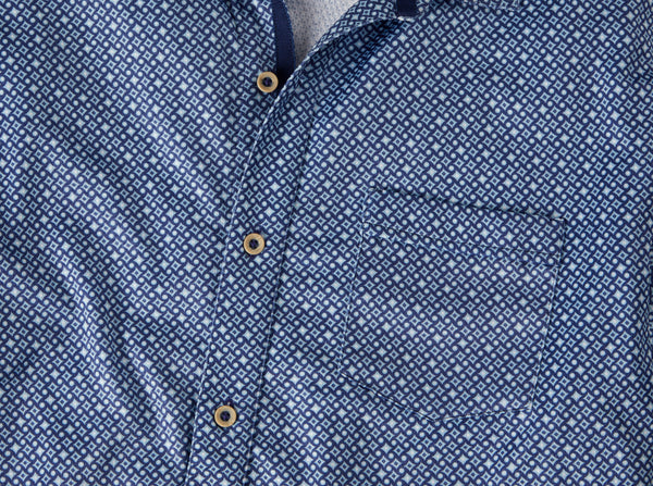 Close-up of a blue and white patterned button-down shirt with brown buttons, showing the collar, front placket, and chest pocket.