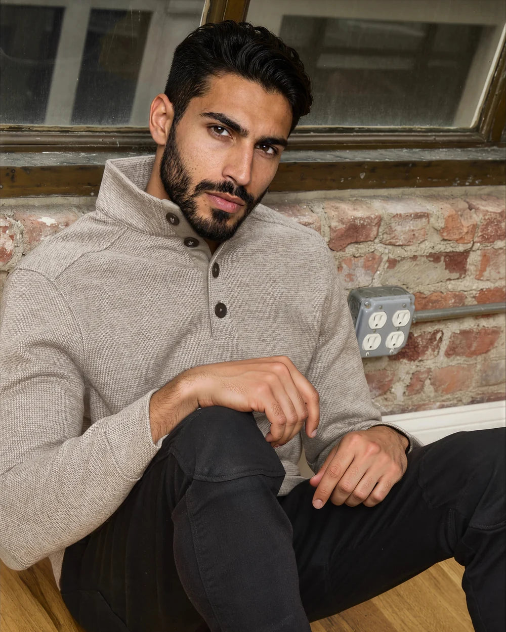 Supplied model seated in the brown Micro-Geometric 4-Button Pullover